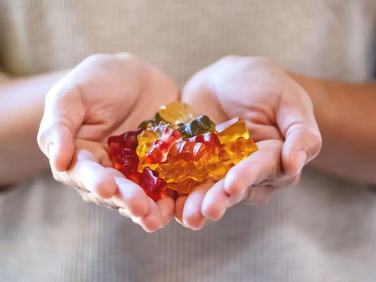 Garść kolorowych żelków w kształcie misiów w dłoniach.