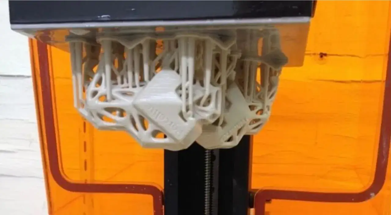 Wydrukowane obiekty z żywicy na platformie drukarki 3D.