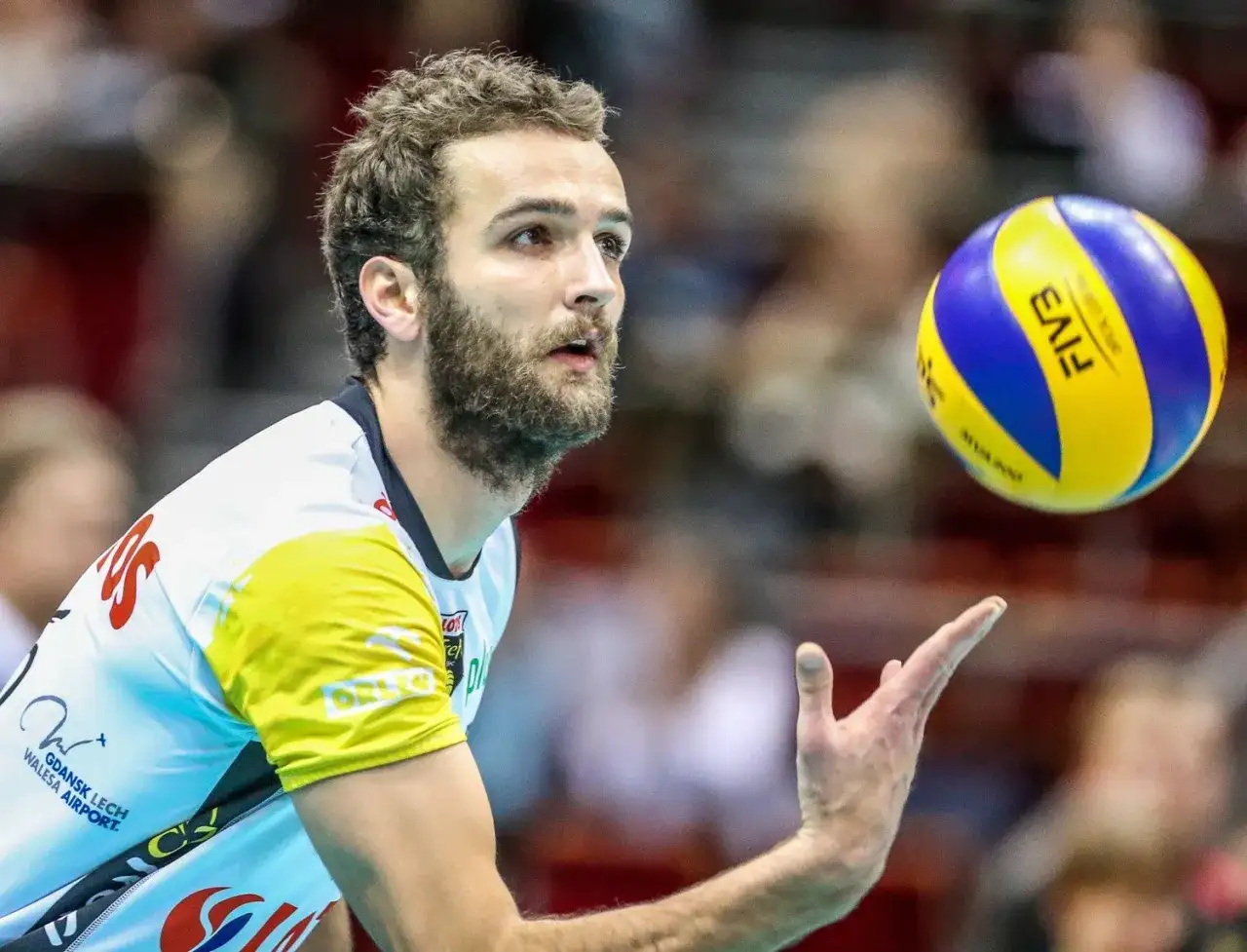 Mateusz Mika, siatkarz, w akcji. Widać jego skupienie i gotowość do przyjęcia piłki.