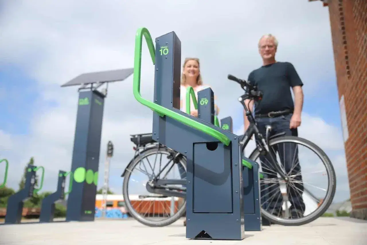 Stacja ładowania rowerów elektrycznych zasilana energią słoneczną. Para ludzi korzysta z nowoczesnych stojaków.