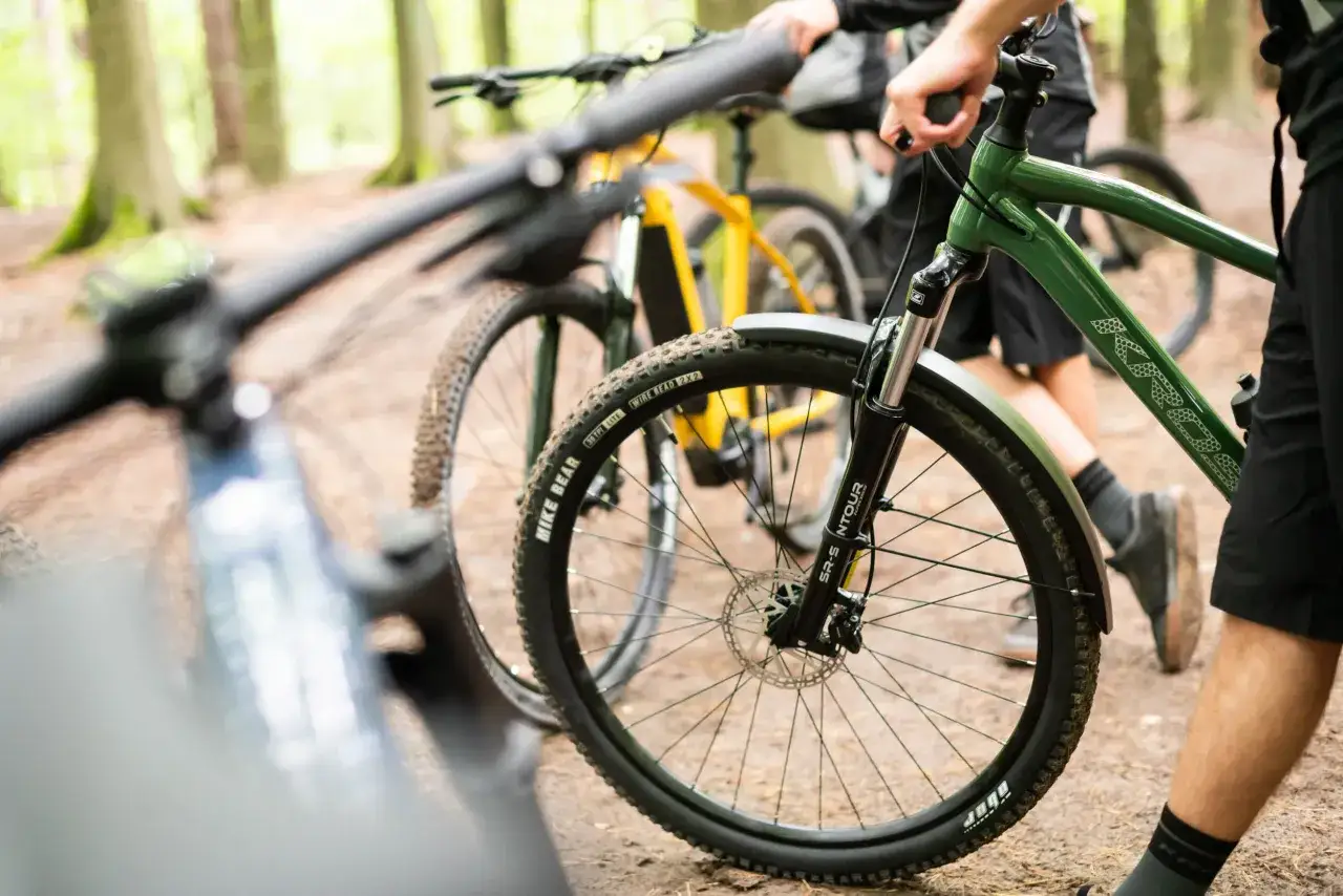 Przygotowania do amatorskich rajdów rowerowych w lesie. Dwa rowery górskie, jeden zielony, drugi żółty, stoją na leśnej ścieżce.