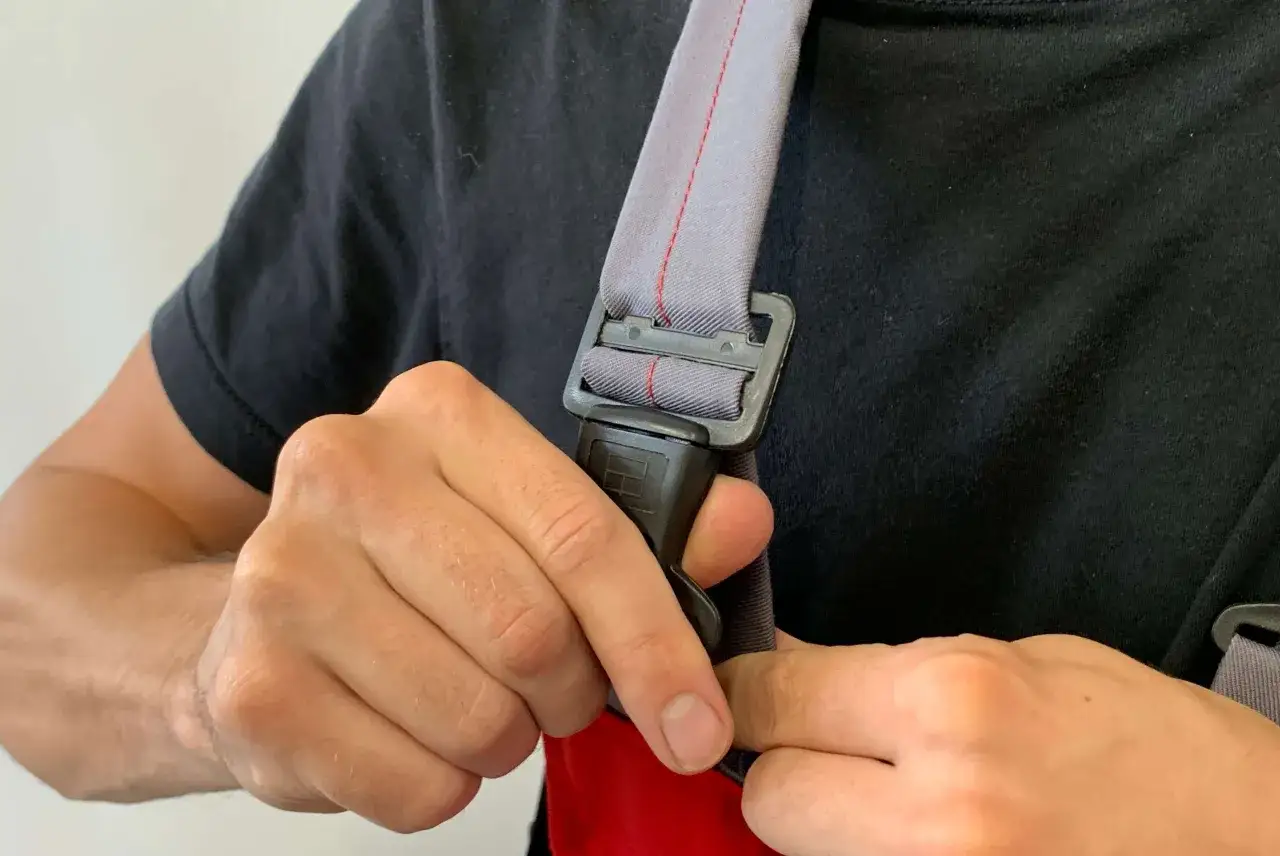 Dłoń zapina klamrę w ogrodniczkach, przygotowując się do pracy.