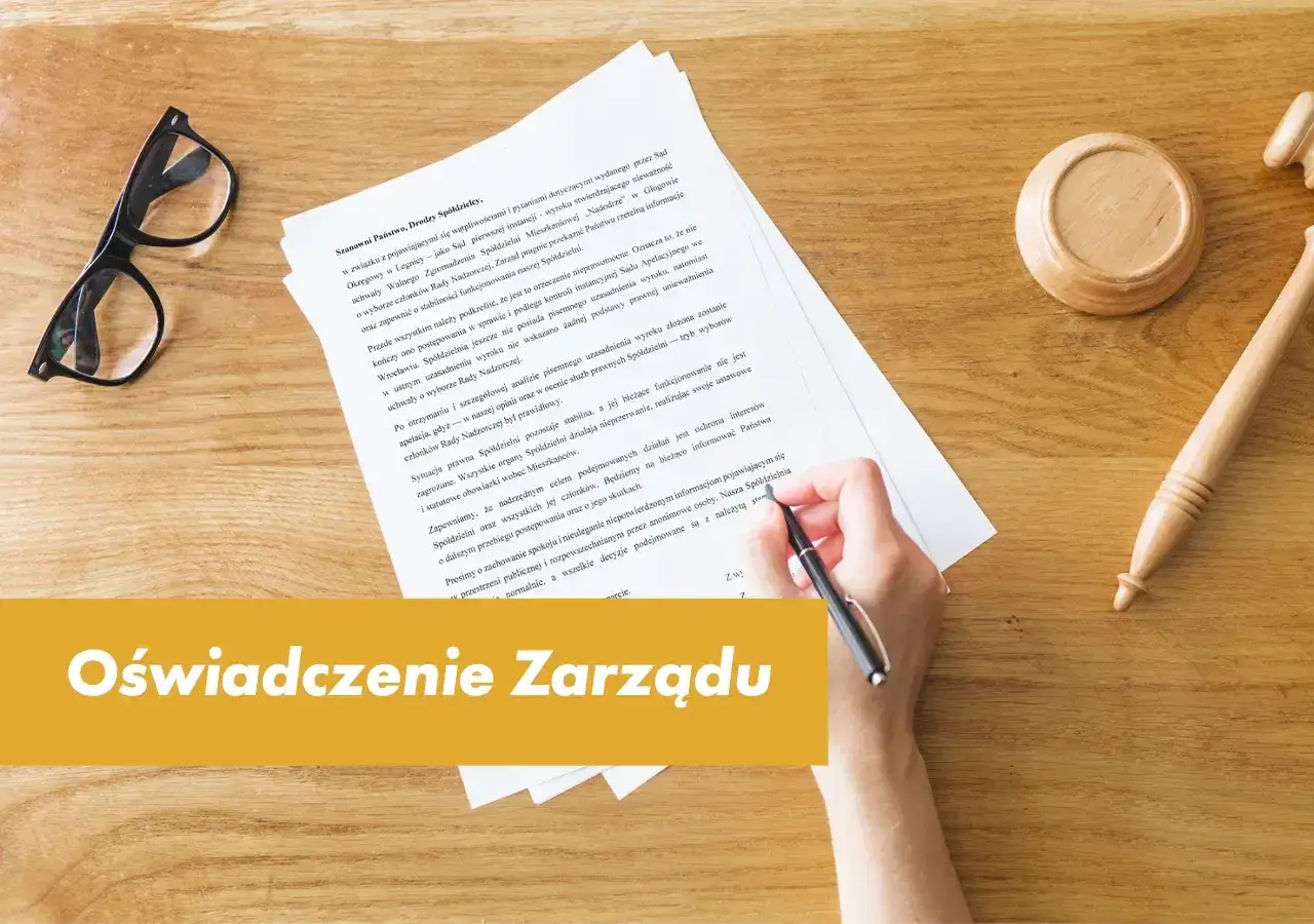 Dłoń pisze dokument, obok okulary i młotek sędziowski. Dowiedz się, jak napisać podanie do spółdzielni mieszkaniowej.