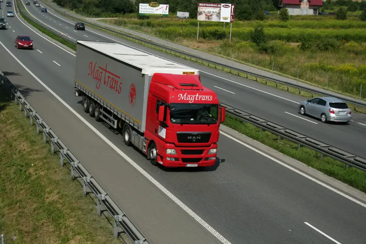 Czerwony tir Magtrans jedzie autostradą. Kierowca może otrzymać mandat za wyprzedzanie tirem w niewłaściwym miejscu.