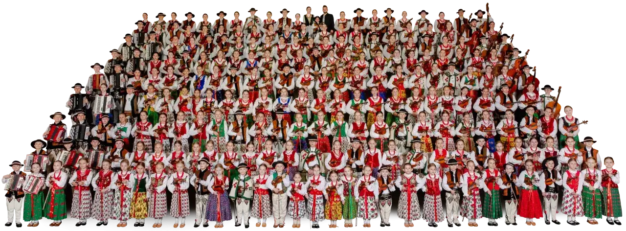 Wielka grupa dzieci i młodzieży w strojach ludowych, grających na akordeonach i skrzypcach. To piękna prezentacja muzyki ludowej Mazowsza.