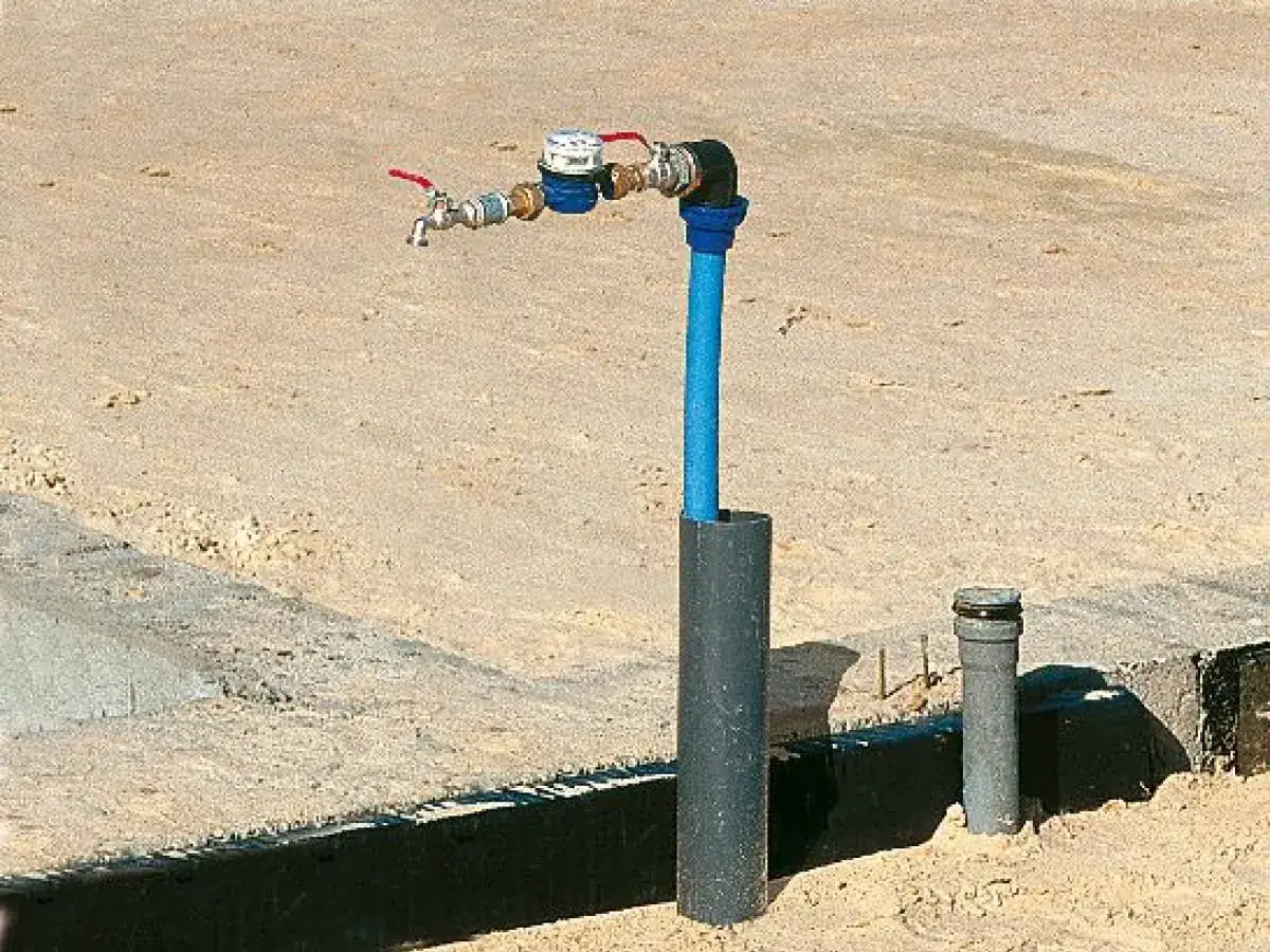 Nowy wodomierz i zawór z czerwonymi uchwytami, podłączenie do istniejącego przyłącza.