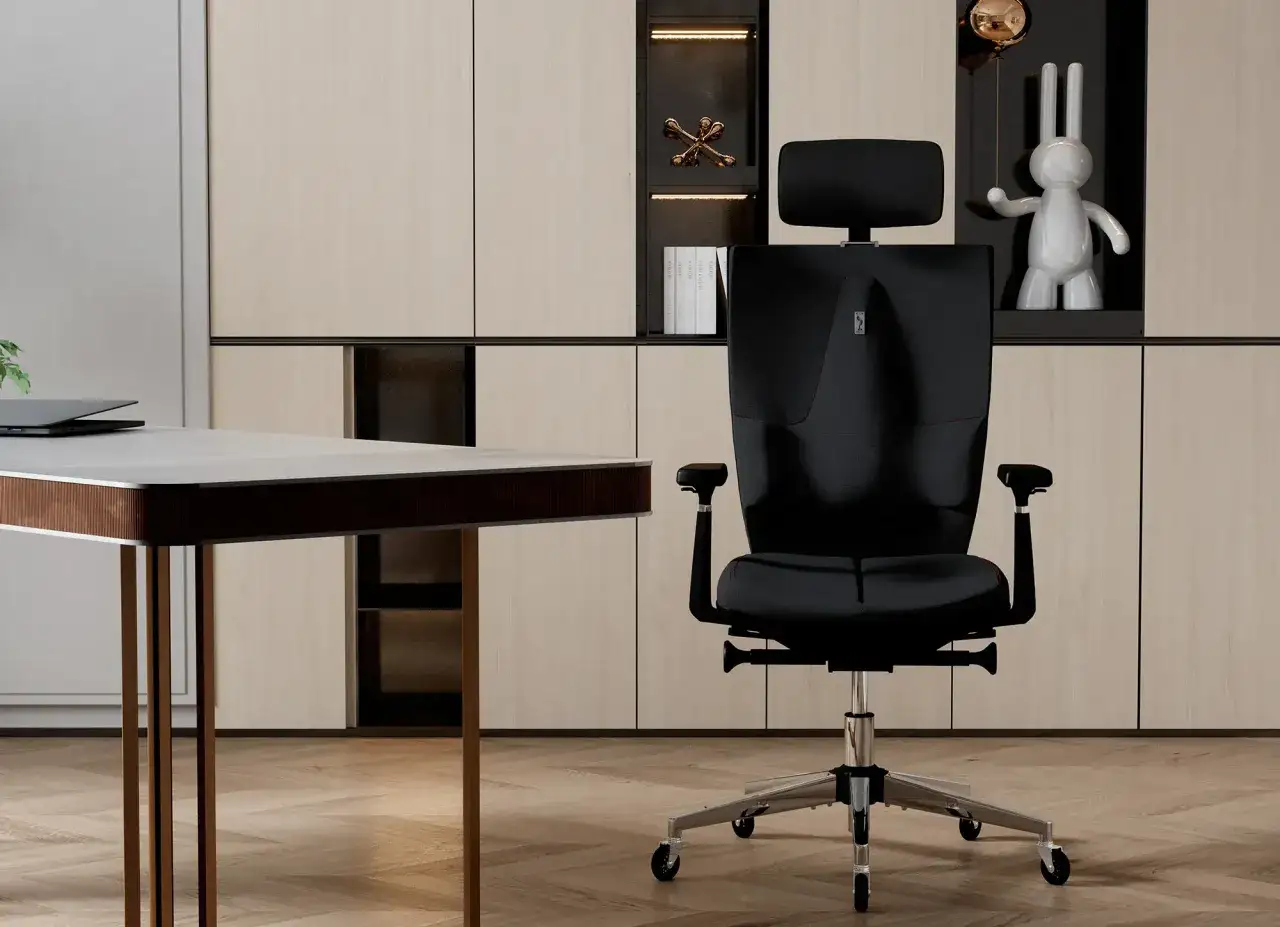 Ergonomiczne czarne krzesło biurowe z zagłówkiem, stojące obok biurka w nowoczesnym gabinecie.