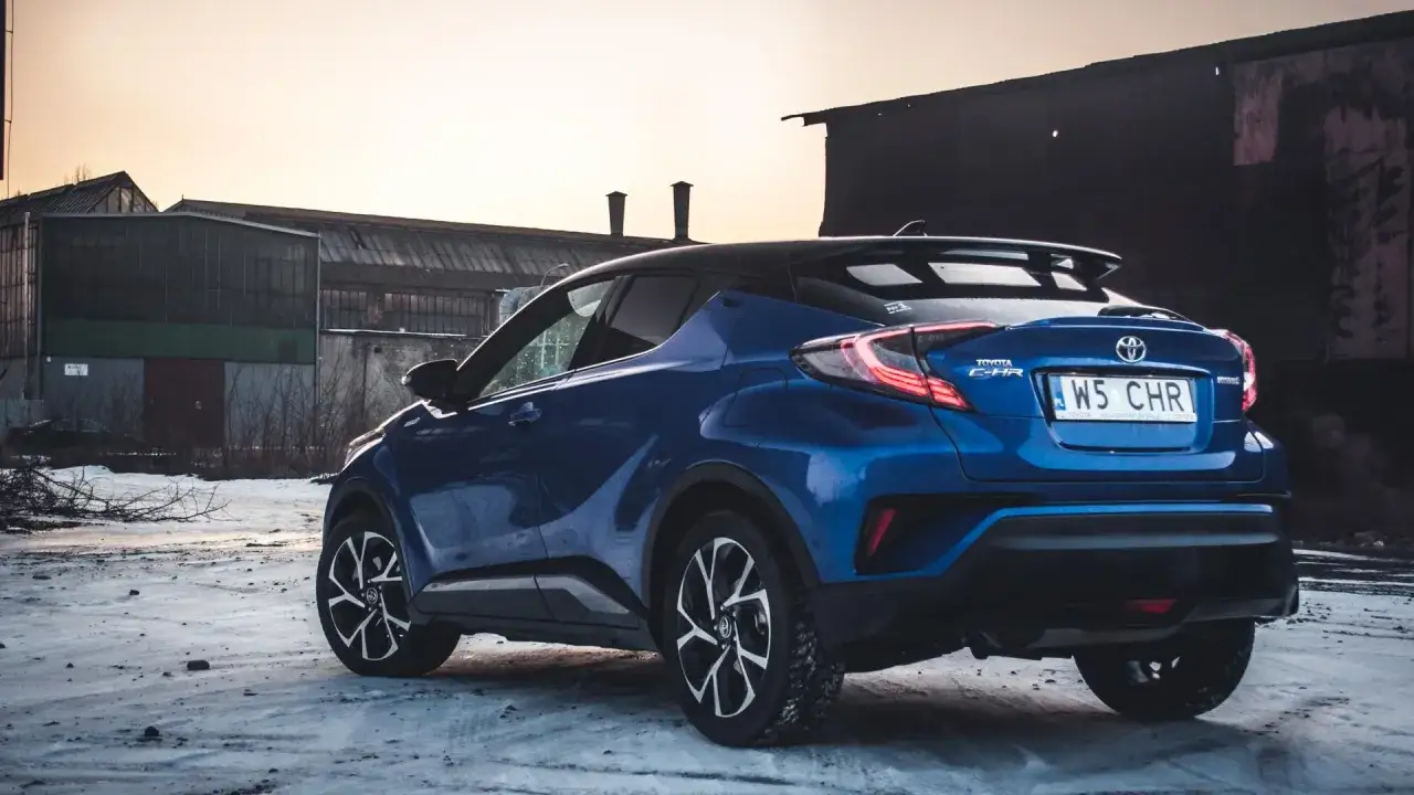 Niebieska Toyota C-HR Hybrid na tle opuszczonych budynków. Czy wybrać hybrydę czy benzynę?