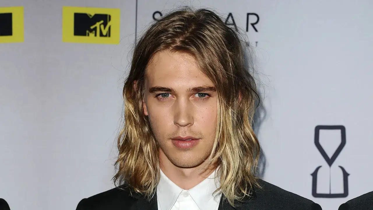 Austin Butler z długimi, falowanymi włosami, który udowadnia, komu pasują długie włosy męskie.