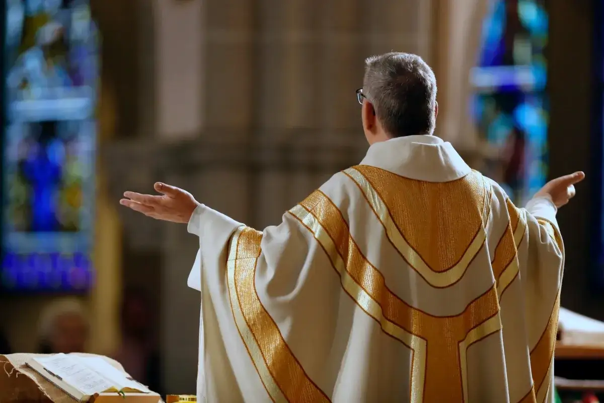 Kapłan w złotej dalmatyce, z rękami rozłożonymi, przygotowuje się do procesji z darami.