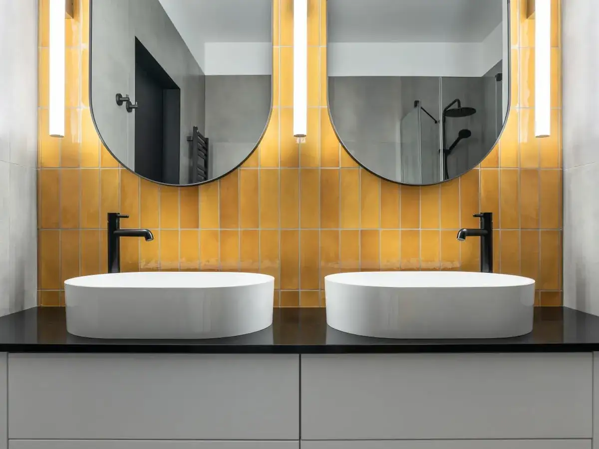 Nowoczesna łazienka z dwoma białymi umywalkami nablatowymi i żółtą mozaiką.