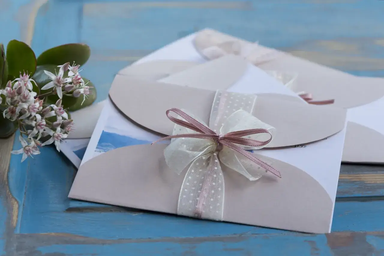 Eleganckie zaproszenia ślubne z kokardkami. Jak odmówić przyjścia na wesele? Delikatne kwiaty dodają uroku.