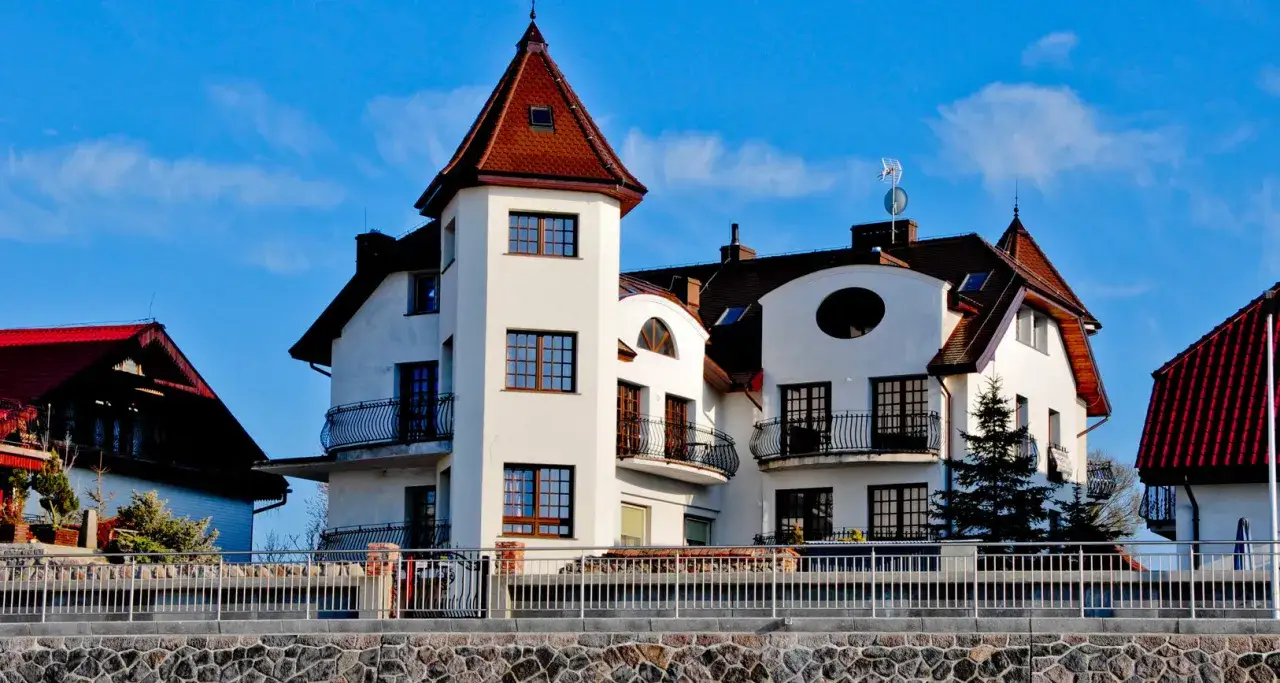 Elegancki dom przy plaży Sarbinowo z wieżyczką i balkonami, pod błękitnym niebem.