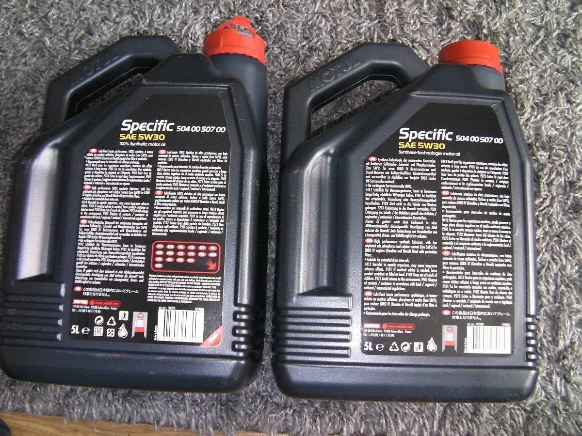Dwie czarne bańki oleju silnikowego Motul Specific SAE 5W30. Sprawdzenie oryginalności produktu jest kluczowe.