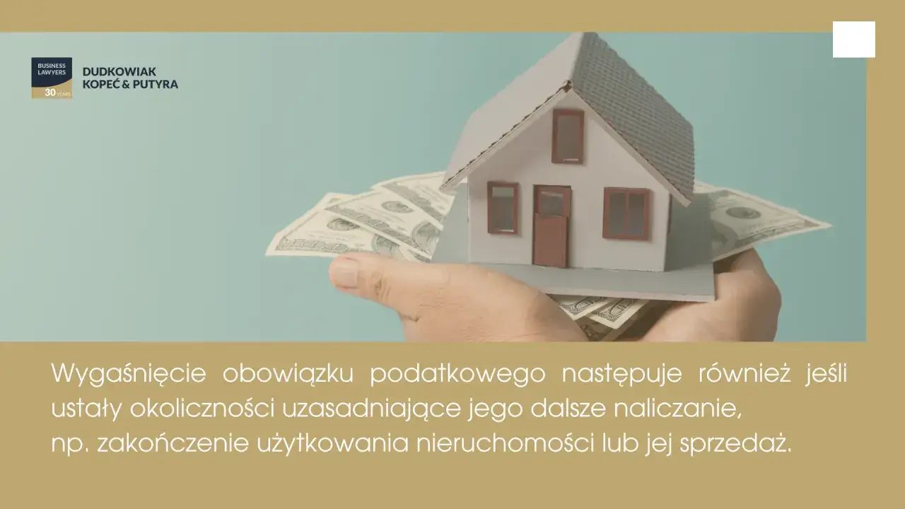 Dłoń trzyma model domu na stosie banknotów dolarowych.