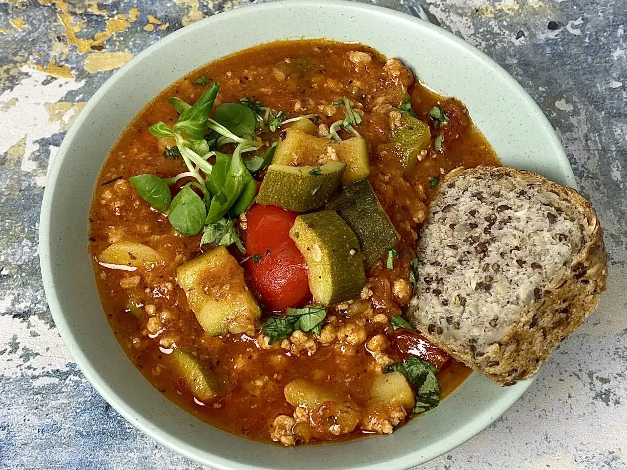 Gulasz z cukinii i pomidorów z mielonym mięsem, podany z chlebem pełnoziarnistym. Idealne danie, gdy zastanawiasz się, co zrobić dobrego na obiad.