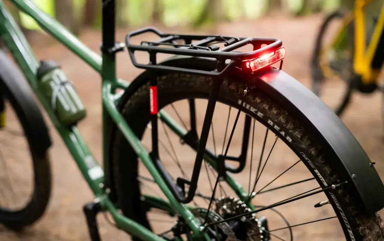 Zielony rower z zamontowanym bagażnikiem rowerowym i czerwoną lampką. Gotowy na wyprawę!