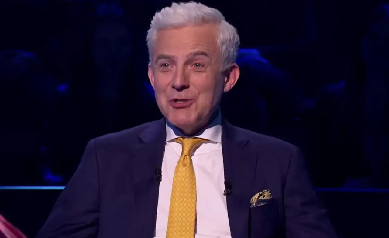 Prowadzący w garniturze z żółtym krawatem, jakby zapowiadał specjalne wydanie "Milionerzy Walentynki gdzie obejrzeć".