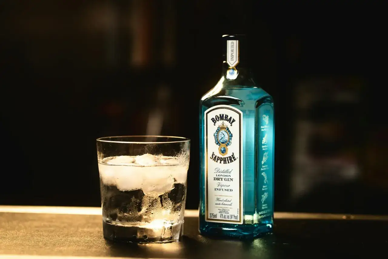 Szklanka z lodem i butelka Bombay Sapphire gin. Idealny składnik na orzeźwiający bombay sapphire drink.