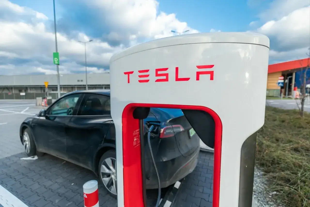 Czarna Tesla podłączona do ładowarki Supercharger.
