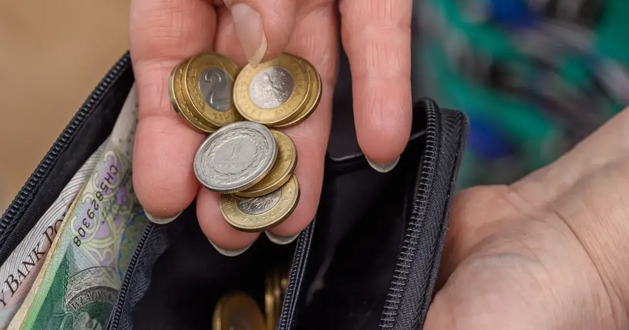 Dłoń z monetami i banknotami w portfelu. Czy to wystarczy na emeryturę po 40 latach pracy? Kalkulator emerytalny pomoże to sprawdzić.