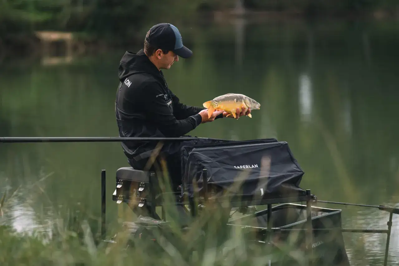 Wędkarz trzyma złowionego karpia. Czy melasa na jakie ryby działa? Ten okaz sugeruje, że tak!