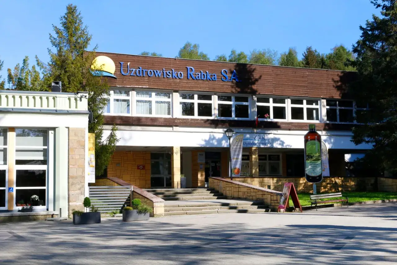Sanatorium Jagiellonka w Rabce-Zdroju, budynek z napisem "Uzdrowisko Rabka S.A." i dużą butelką solanki.