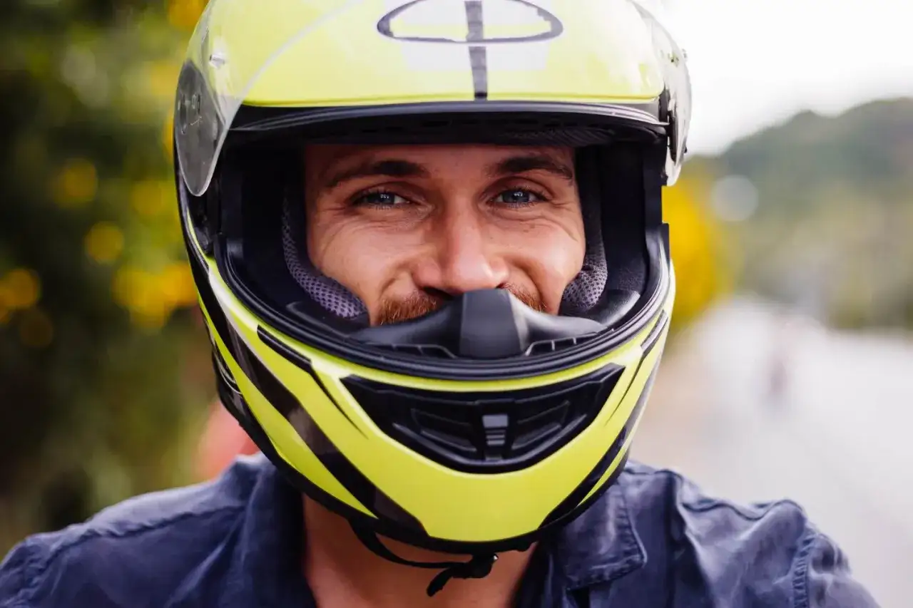 Uśmiechnięty mężczyzna w żółtym kasku motocyklowym. Dobór odpowiednich rozmiarów kasków motocyklowych to klucz do bezpieczeństwa.