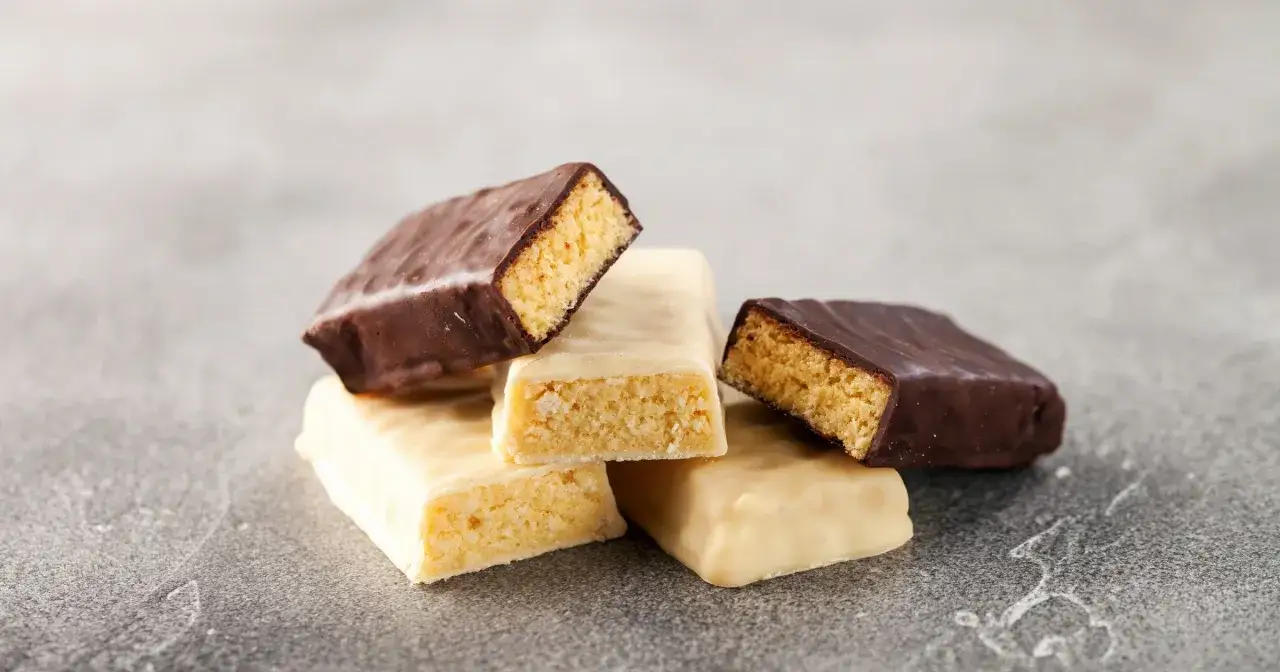 Kilka batonów proteinowych, polanych czekoladą i białą polewą, pokazuje, co dają batony proteinowe: szybką energię i wsparcie dla mięśni.