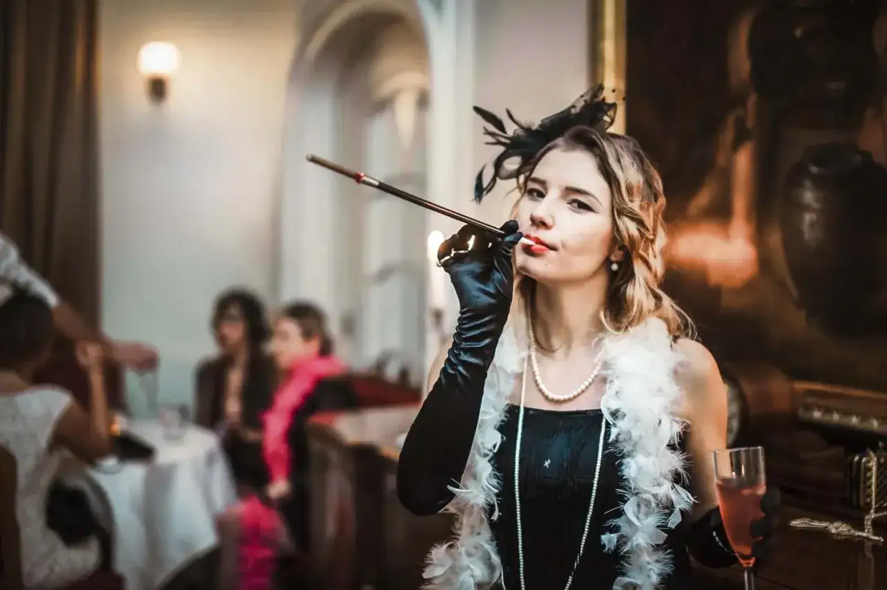 Kobieta w stylu lat 20. z cygaretką i piórami, na tle imprezy.