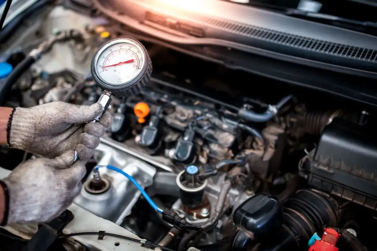 Mechanik sprawdza jakie ciśnienie sprężania w dieslu za pomocą manometru.