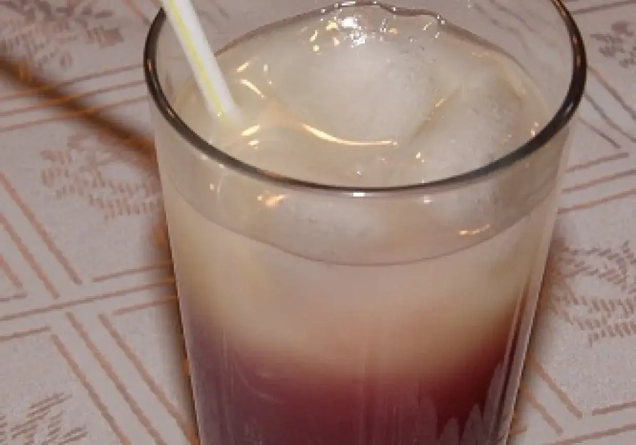 Szklanka z drinkiem z lodem i słomką, z widocznym podziałem na warstwy koloru.