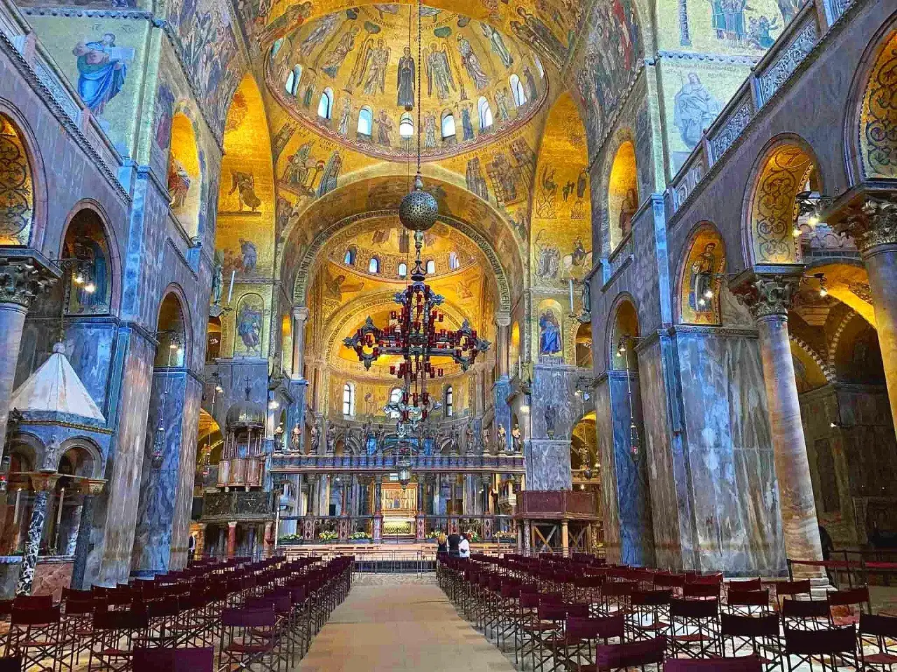 Wnętrze Bazyliki św. Marka w Wenecji, olśniewające złotymi mozaikami i marmurowymi kolumnami.