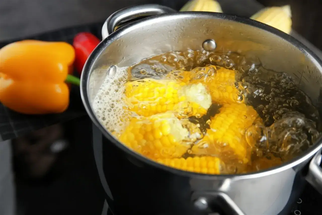 Kukurydza gotuje się w garnku. Dowiedz się, jak długo gotować kukurydzę na ryby, by była idealna. Obok papryka.