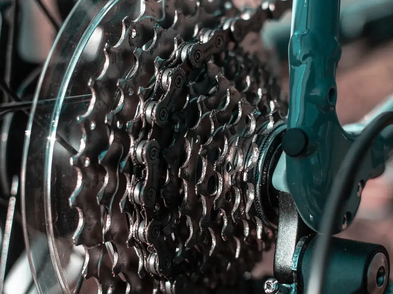 Zbliżenie na kasetę zębatek rowerowych i mocowanie przerzutki tylnej. Metalowe zębatki i łańcuch tworzą skomplikowany mechanizm.