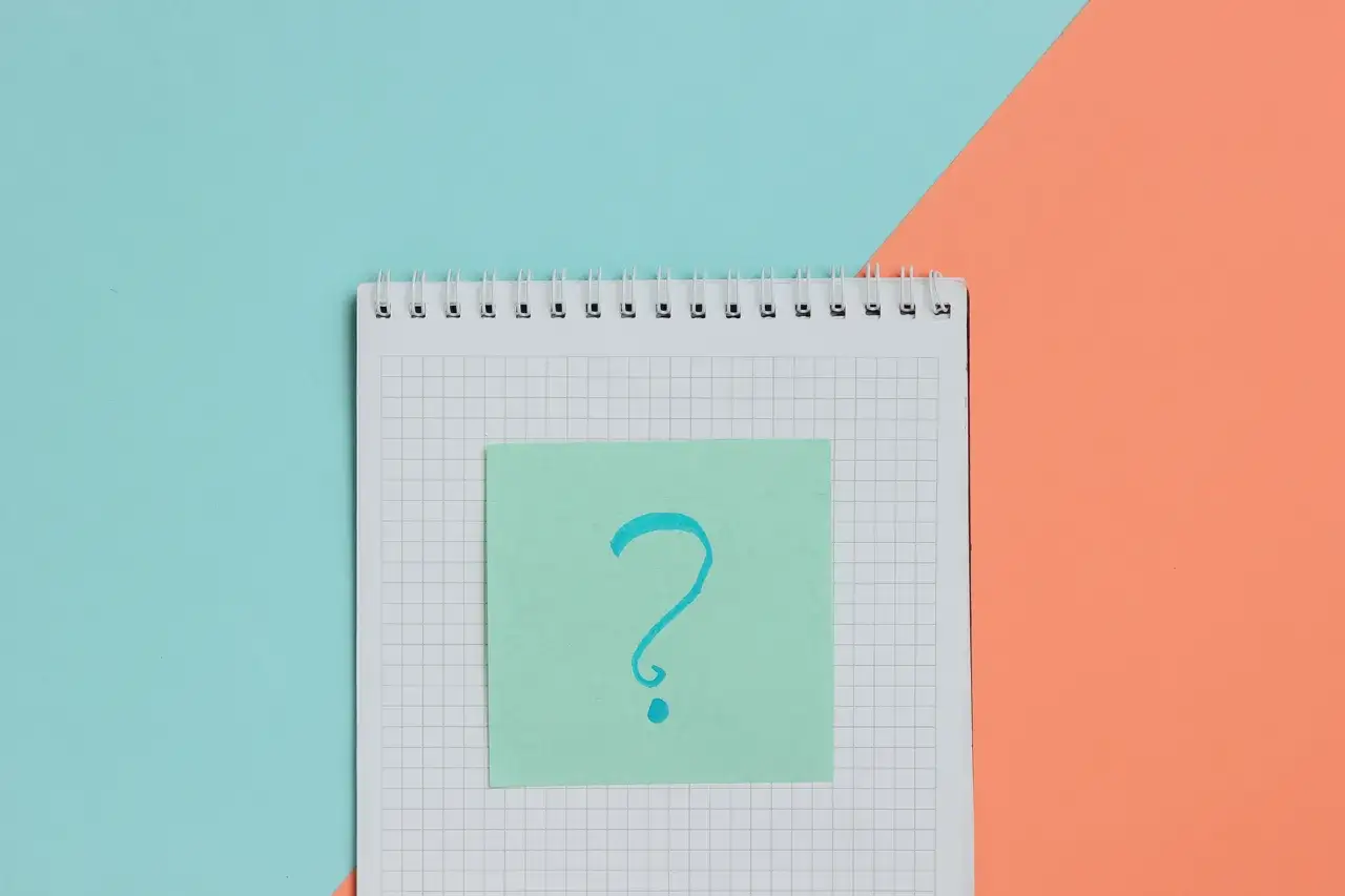 Notatnik z pytajnikiem na zielonej karteczce. Tak jak wyglądają badania do szkoły średniej – pełne pytań i niepewności.