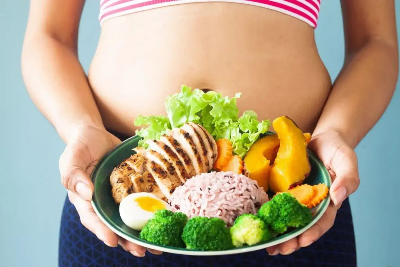 Zdrowa dieta to klucz do tego, jak zgubić oponkę z brzucha. Na talerzu grillowany kurczak, ryż, jajko i warzywa.