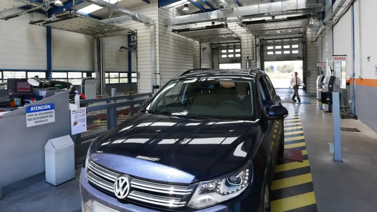 Coche oscuro en una estación de inspección técnica de vehículos (ITV) con un técnico al fondo.