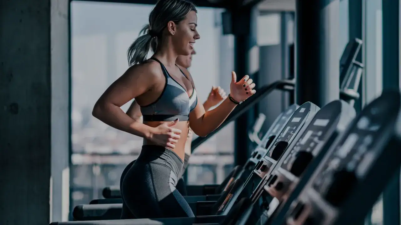 Kobiety biegnące na bieżniach w siłowni.