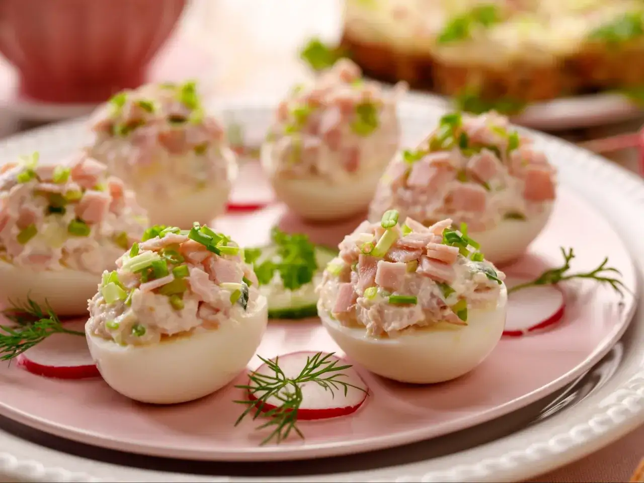Pyszne jajka faszerowane z szynką i szczypiorkiem, udekorowane rzodkiewką i koperkiem. Idealna przekąska na każdą okazję.