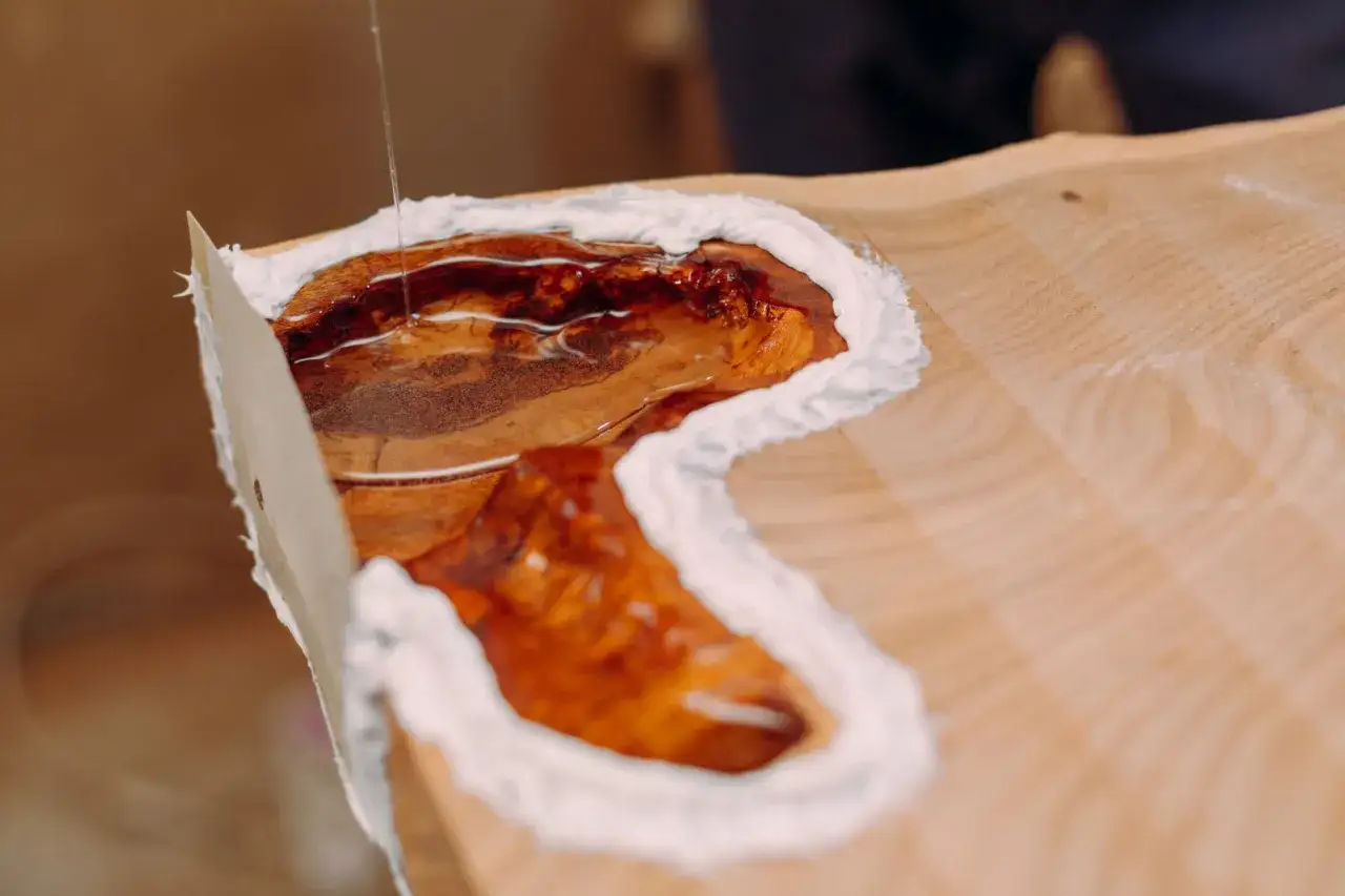 Praca z żywicą epoksydową: płynna żywica wypełnia drewniane wgłębienie, tworząc efektowny blat.