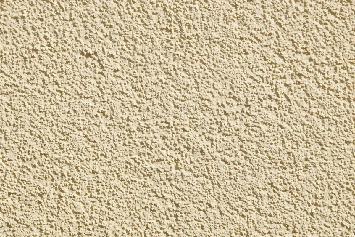 Beżowa, chropowata ściana z tynkiem strukturalnym. Dowiedz się, jak usunąć tynk strukturalny z elewacji.