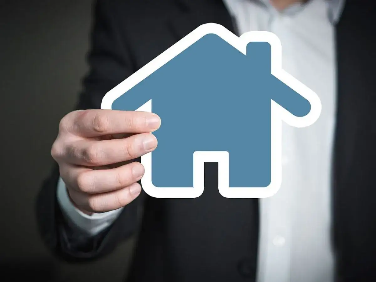 Dłoń trzyma niebieski symbol domu. Zastanawiasz się, ile się czeka na pozwolenie na budowę?