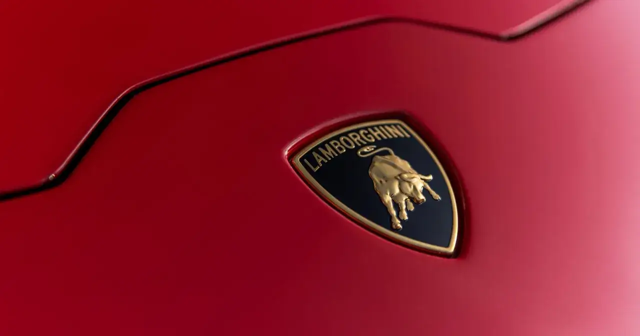 Złoty byk na czarnym tle z napisem "Lamborghini" - tak wygląda znaczek tej marki na czerwonej karoserii.