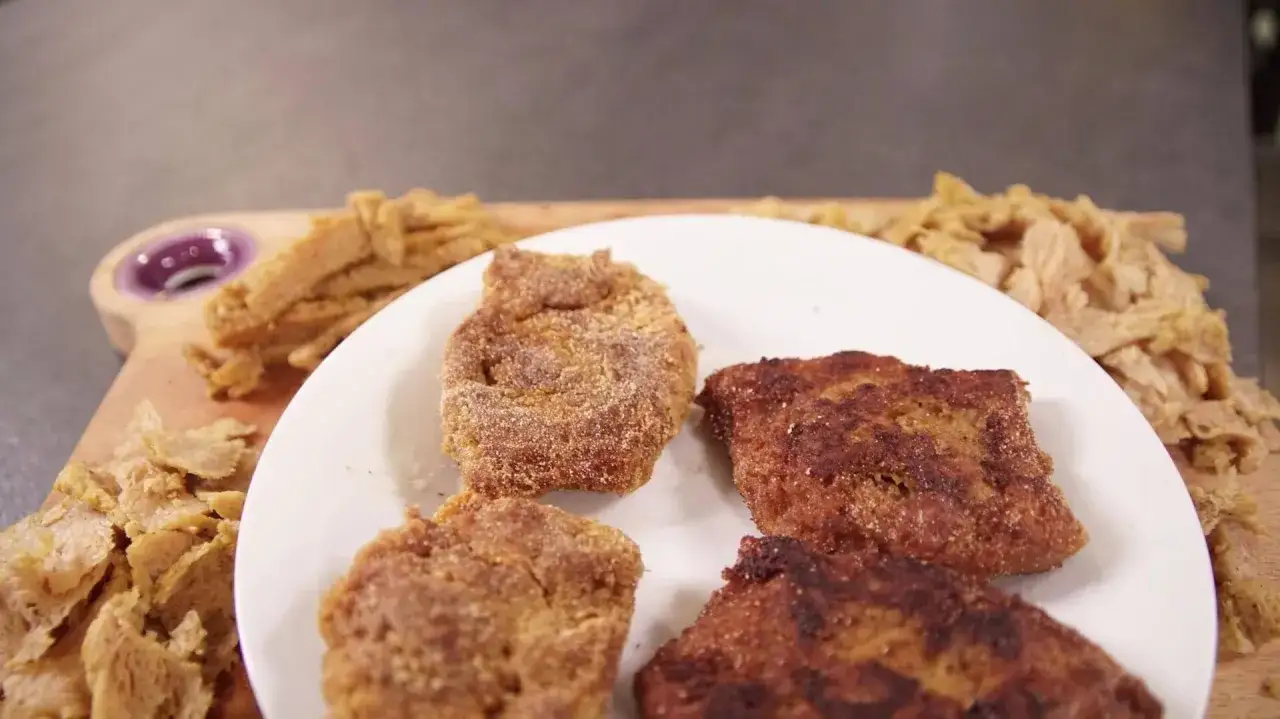 Kotlety sojowe na talerzu i surowe kawałki soi na desce.