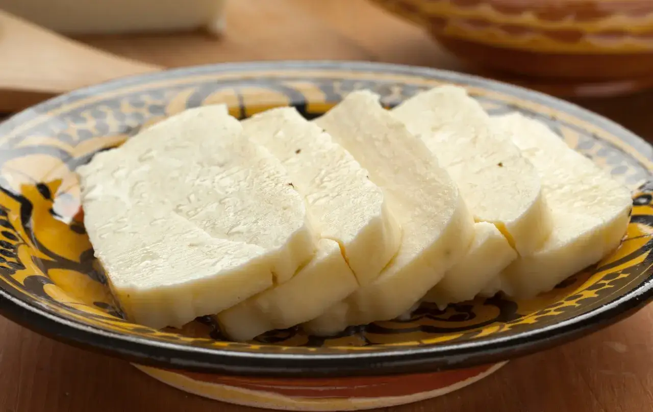 Pokrojony w plastry domowy ser halloumi na ozdobnym talerzu.