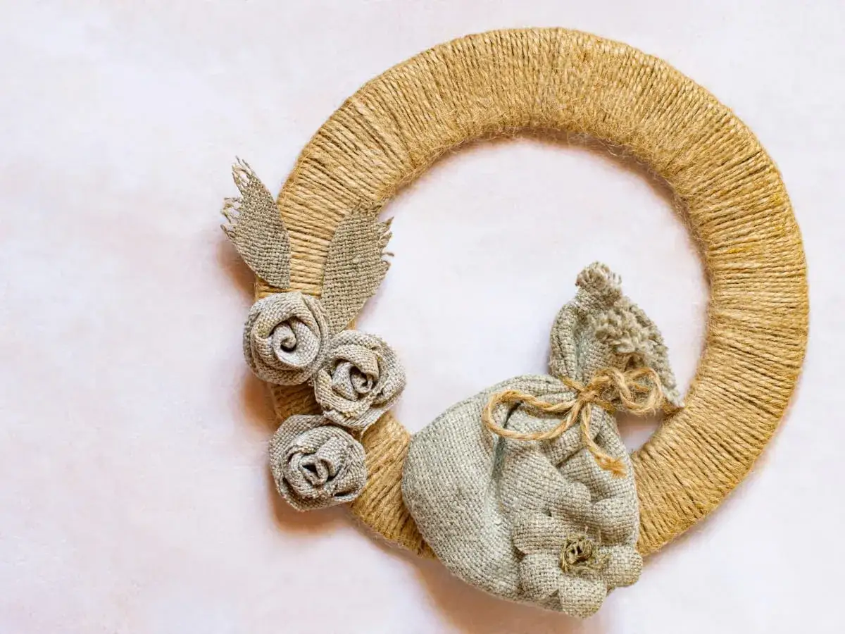 Odkryj cuda ze sznurka jutowego: wianek ozdobiony różyczkami i woreczkiem z tkaniny.