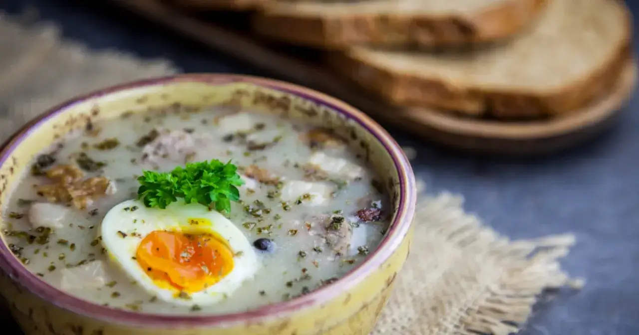 Żur z jajkiem i majerankiem, idealne jakie przyprawy do żuru. Obok kromki chleba.