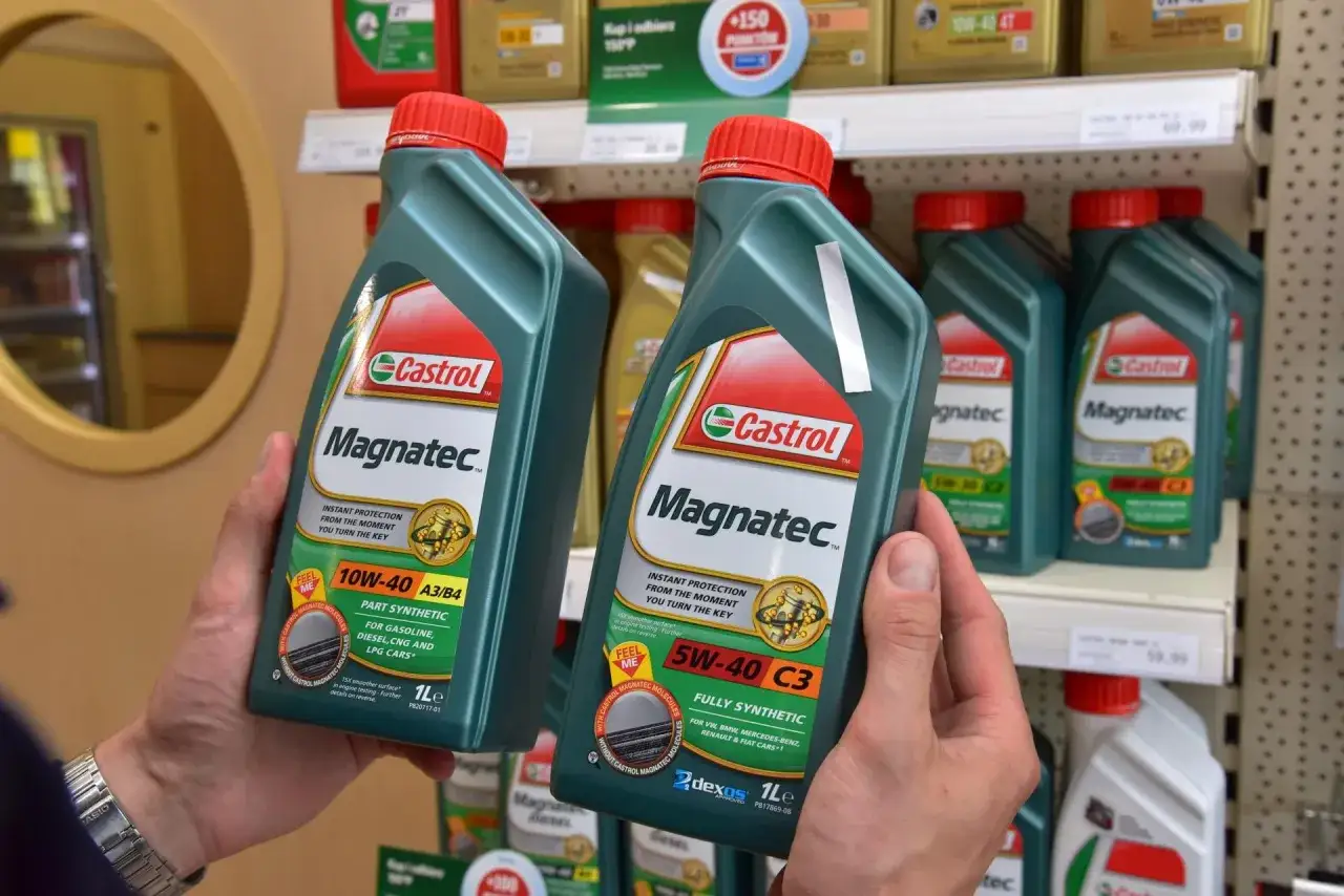 Ręce trzymają butelki oleju silnikowego Castrol Magnatec. Czy Castrol to dobry olej? Ten produkt zapewnia natychmiastową ochronę silnika.