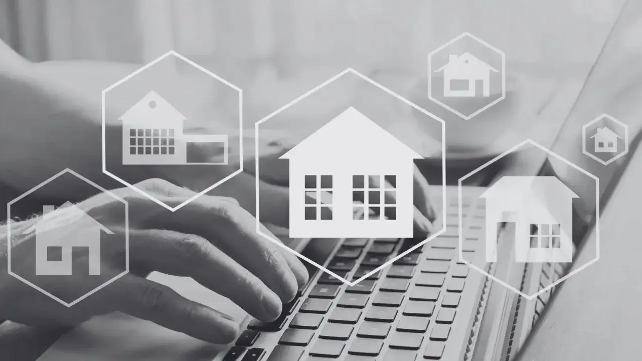 Dłonie piszące na klawiaturze laptopa otoczone ikonami domów w heksagonach.